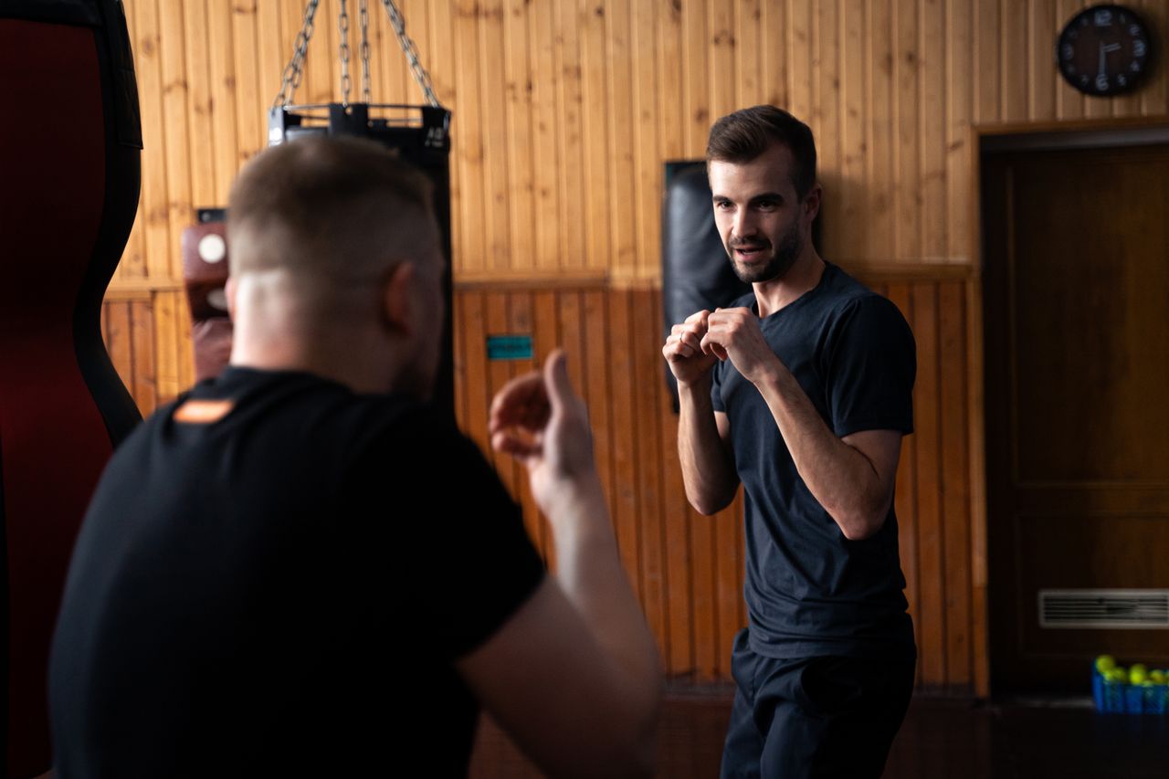 Two men sparring in a boxing gym, focusing on technique and movement.