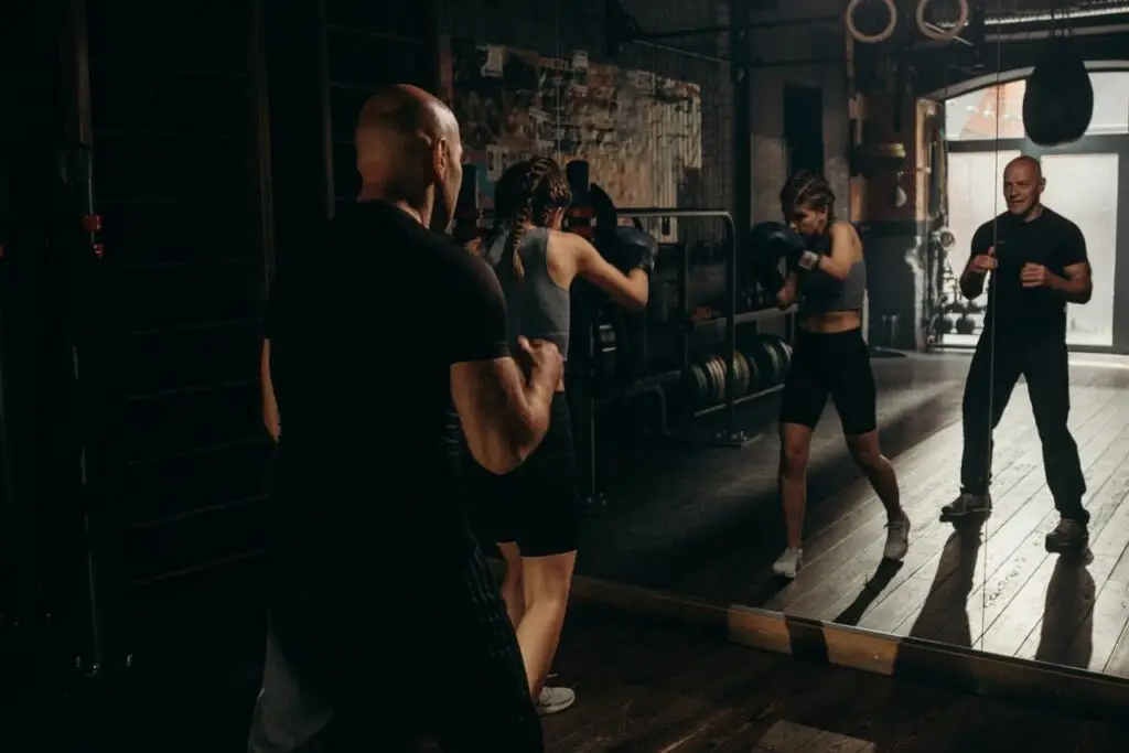 Focused female boxer trains with coaches in an indoor gym setting, showcasing strength and determination.