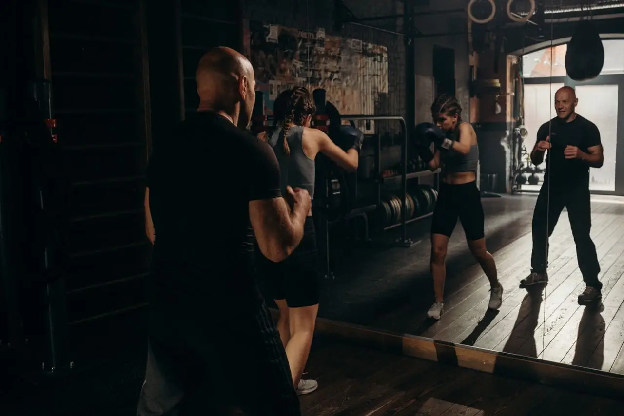 Focused female boxer trains with coaches in an indoor gym setting, showcasing strength and determination.