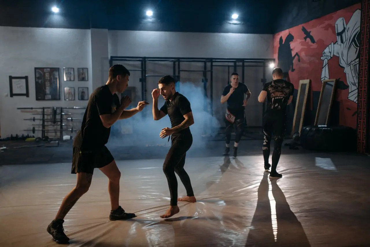 Intense MMA sparring session with fighters training in a dimly lit gym.
